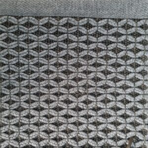 Et håndvevd teppe med en tydelig strukturert overflate. Teppet har en levende melering og en diskret kantavslutning