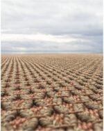 Et håndvevd teppe med en tydelig strukturert overflate. Teppet har en levende melering og en diskret kantavslutning