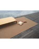 Et håndvevd teppe med en tydelig strukturert overflate. Teppet har en levende melering og en diskret kantavslutning