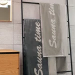 Grått frottéhåndkle til sauna i 100% bomull med teksten 'Sauna time