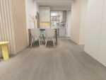Titan Klikkvinyl Romsdal lagt i et stort, lyst rom. Gulvet har et naturlig treutseende med brede planker i en varm, lys beige nyanse som gir et autentisk preg.