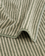 Cawö Two-Tone Stripe-håndkle i fargen Field. Håndkleet har smale, vertikale striper i en olivengrønn nyanse og off-white.