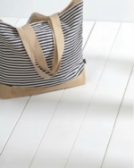 Stor strandveske i canvas med klassiske marineblå og hvite striper, naturfarget bunn i flettet jute og solide skulderremmer.